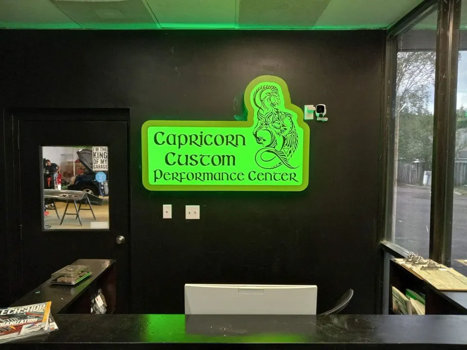 Illuminated green custom business sign displayed inside a storefront